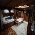 Photo de la cabine arrière du bateau. Cette dernière comprend un lit double situé à gauche, une petite banquette devant ce dernier ainsi qu'un accès à la timonerie du bateau.