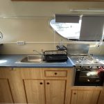 Autre vue de la cuisine avec focus sur l'évier et la plaque de cuisson au gaz.