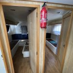 Photo de l'entrée des deux cabines babord et tribord du bateau avec des encadrements de porte en bois.