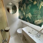 Photo de la salle de bain attenante à la troisième cabine du bateau. Elle est blanche avec, comme pour l'autre salle de bain, un toilette, un évier ainsi qu'un store aux motifs tropic