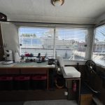 Autre vue de la pièce à vivre avec à droite le poste de pilotage intérieur du bateau et juste après un meuble avec des bacs en-dessous.