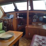 Autre vue de la pièce à vivre avec à gauche le poste de pilotage intérieur et à droite la banquette en cuir bordeaux.