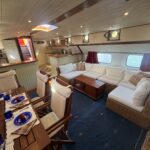 Dutch Luxe-Motor barge Dulcinea (1929) – saloon with dining table, corner sofa and open galley in the background