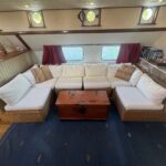 Dutch Luxe-Motor barge Dulcinea (1929) – U-shaped seating area with rattan sofa and wooden chest as coffee table