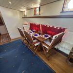 Dutch Luxe-Motor barge Dulcinea (1929) – dining area with laid wooden table and folding chairs