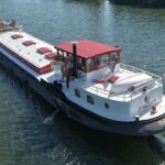 Dutch Luxe-Motor barge Dulcinea (1929) – aerial stern-quarter view underway, wheelhouse with red canopy